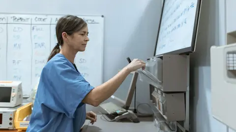 Une infirmière prépare des médicaments à l'armoire à pharmacie du service